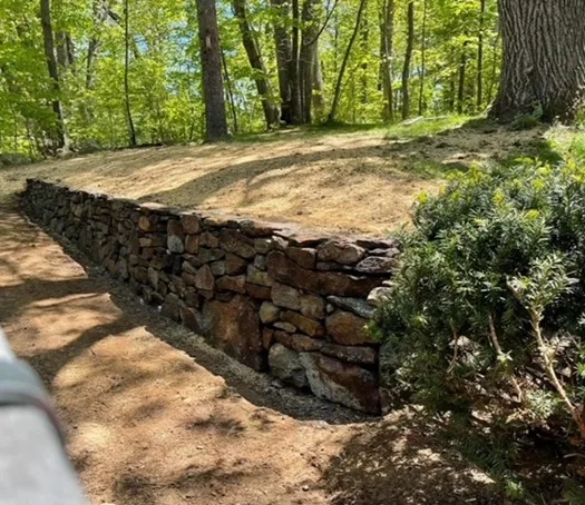 Natural fieldstone retaining wall built into a hillside