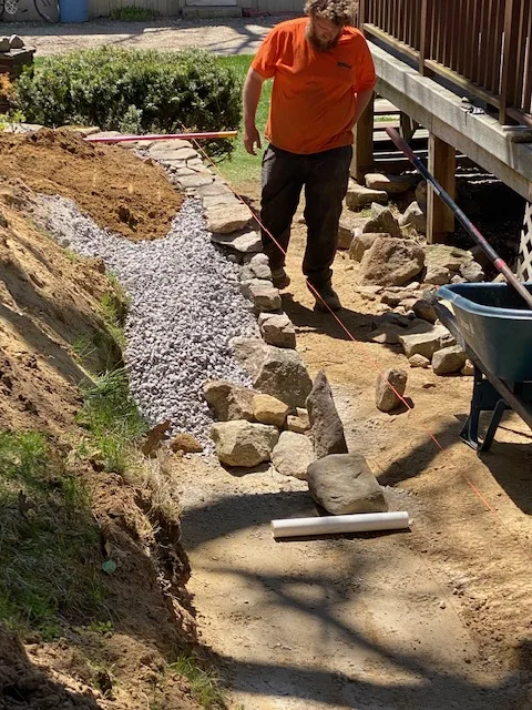 Stone wall under construction — base and backfill in progress